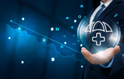 Businessman holding a digital shield with healthcare and cybersecurity icons over a financial graph background, representing modern Cybersecurity Solutions in the healthcare industry.